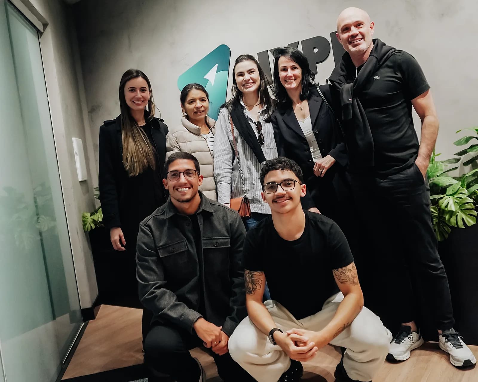 Grupo reunido na recepção da Hype Mídia, diante da marca aplicada na parede